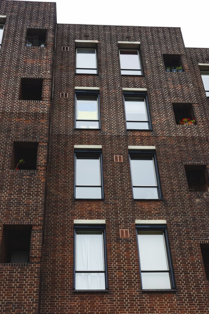 about-01 Vertical shot of a modern brick building facade with windows and architectural details.