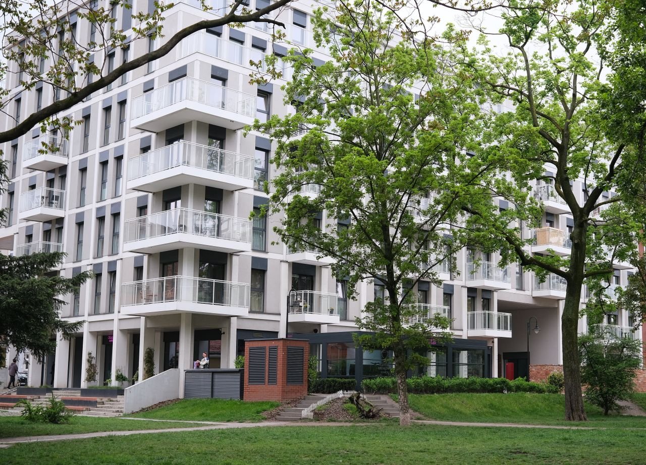 contact-img Contemporary urban apartment complex surrounded by lush trees and greenery.