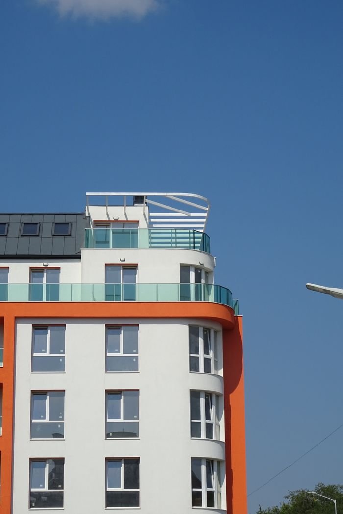 hero-img-01 Contemporary apartment building against a clear blue sky. Ideal for urban architecture concepts.
